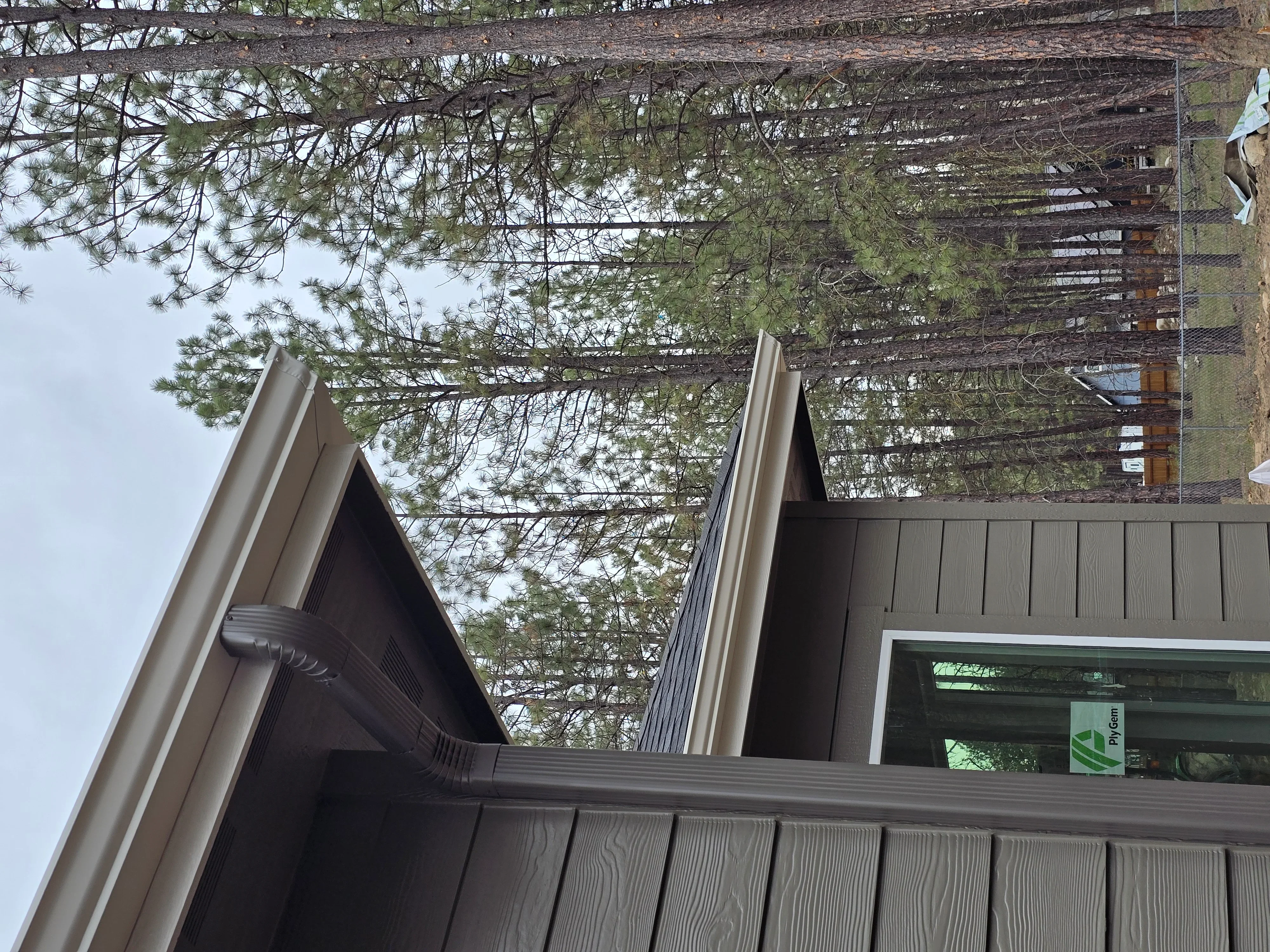 Gray aluminum gutters and fascia installed on residential roofline with downspout