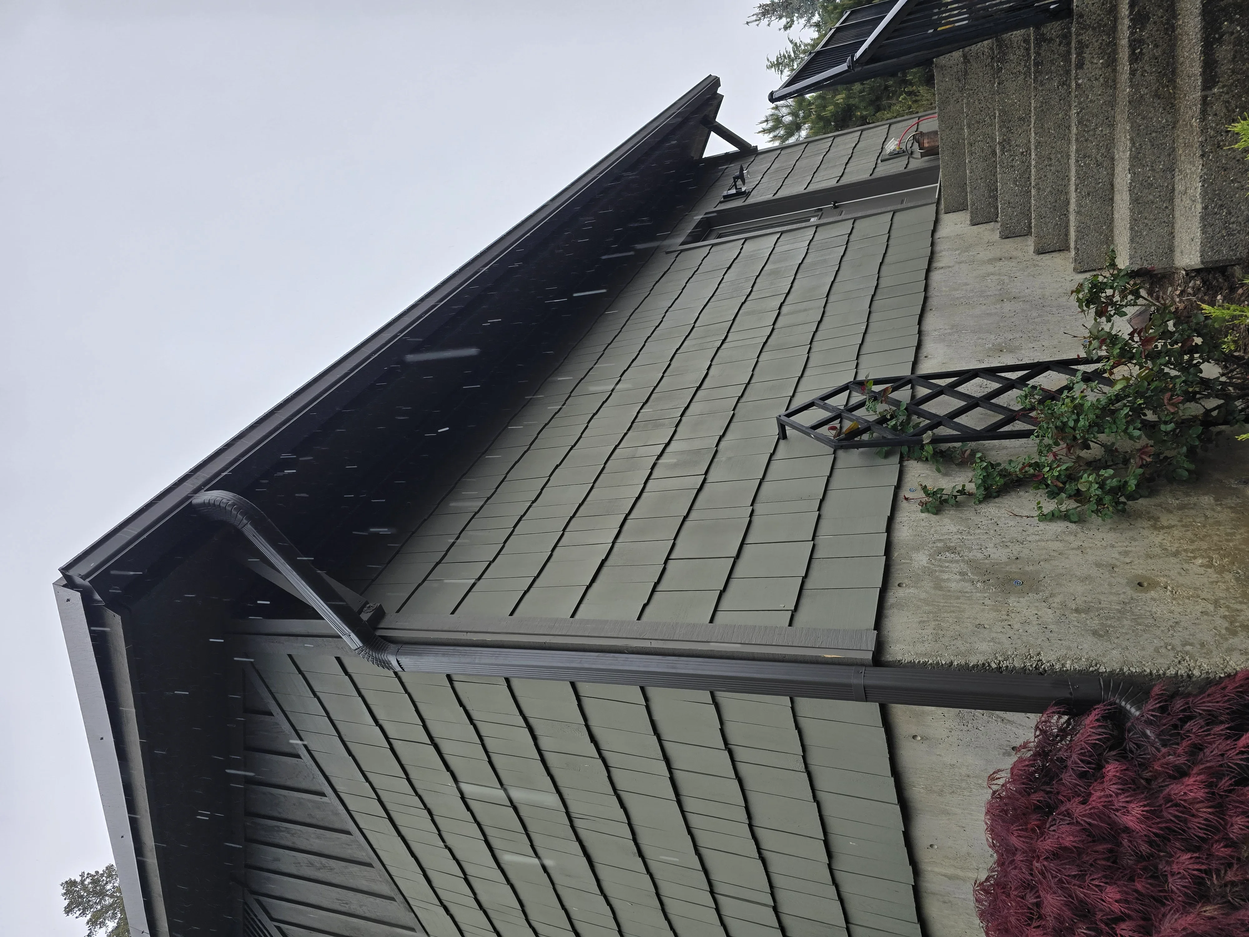Standing seam metal roof with vertical seams, gutters, and concrete chimney detail