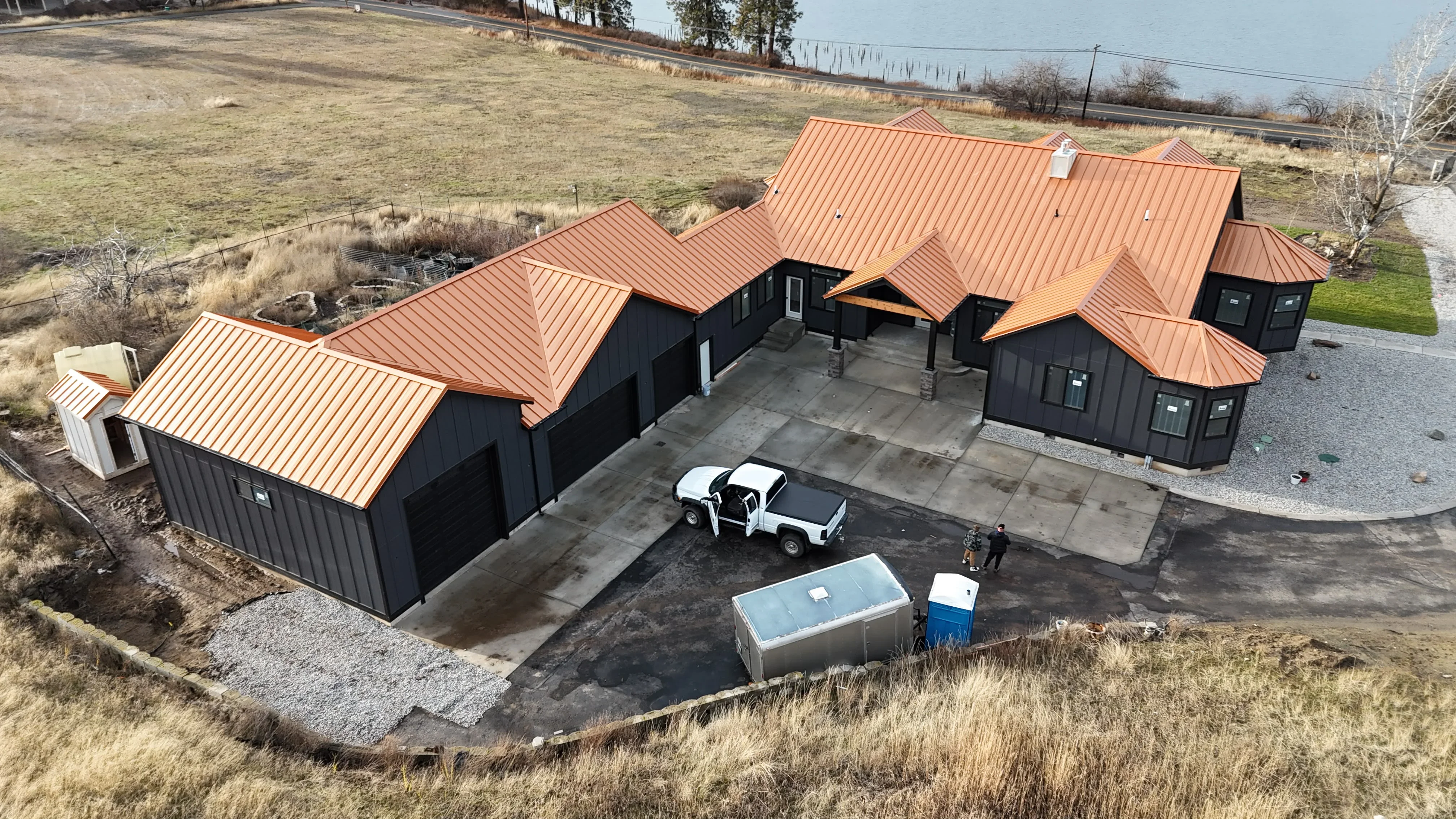 Standing seam copper metal roof on black residential building with multiple peaks and valleys
