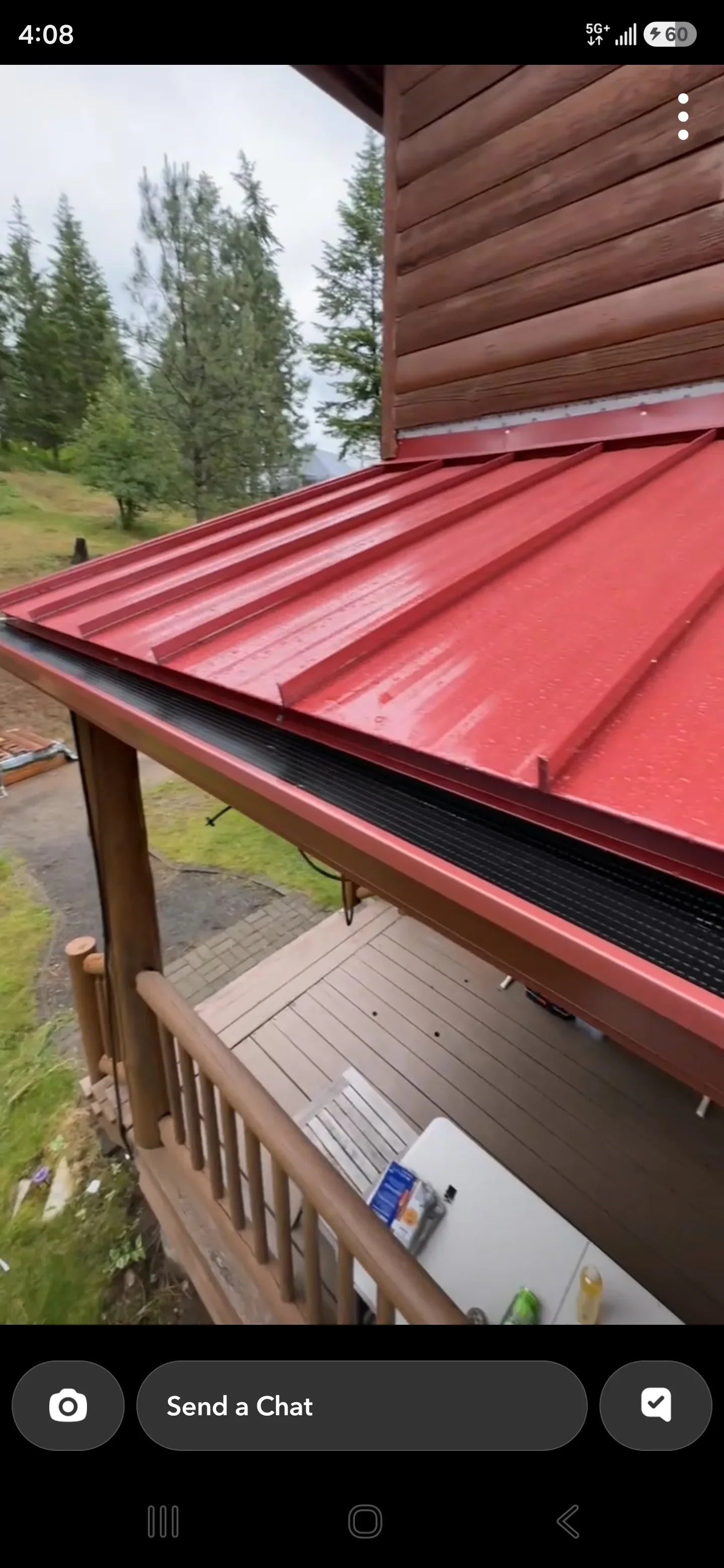 Red standing seam metal roof with clean panel lines and flashing detail against log siding