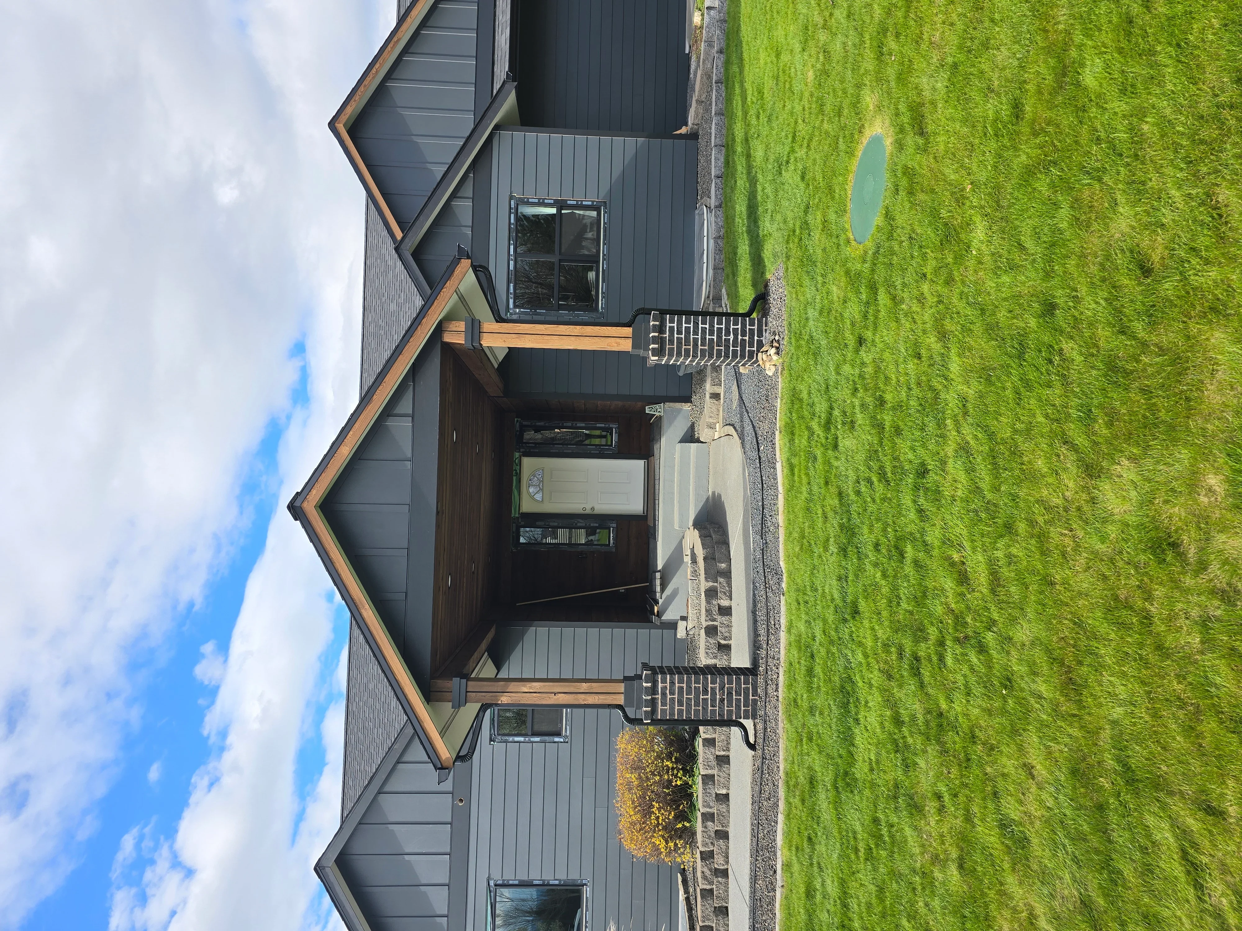 Modern home with charcoal metal standing seam roof, wood trim accents, and metal siding