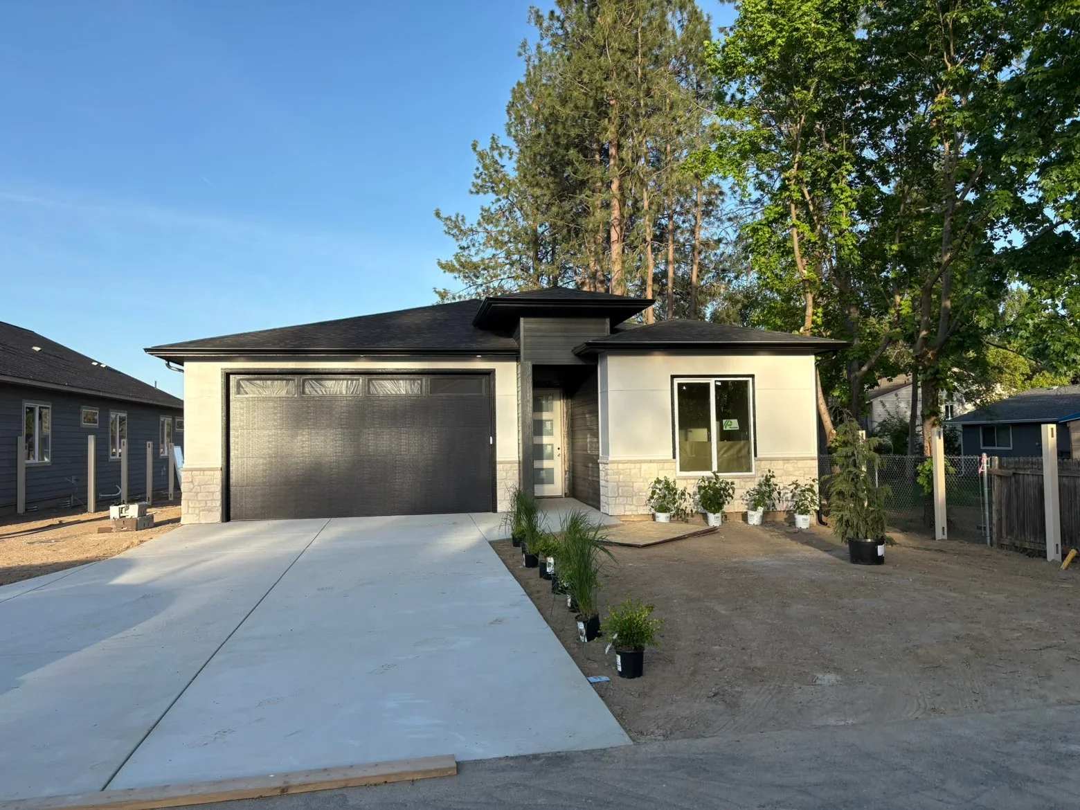 Black asphalt shingle roof on modern home with stone base and black trim details