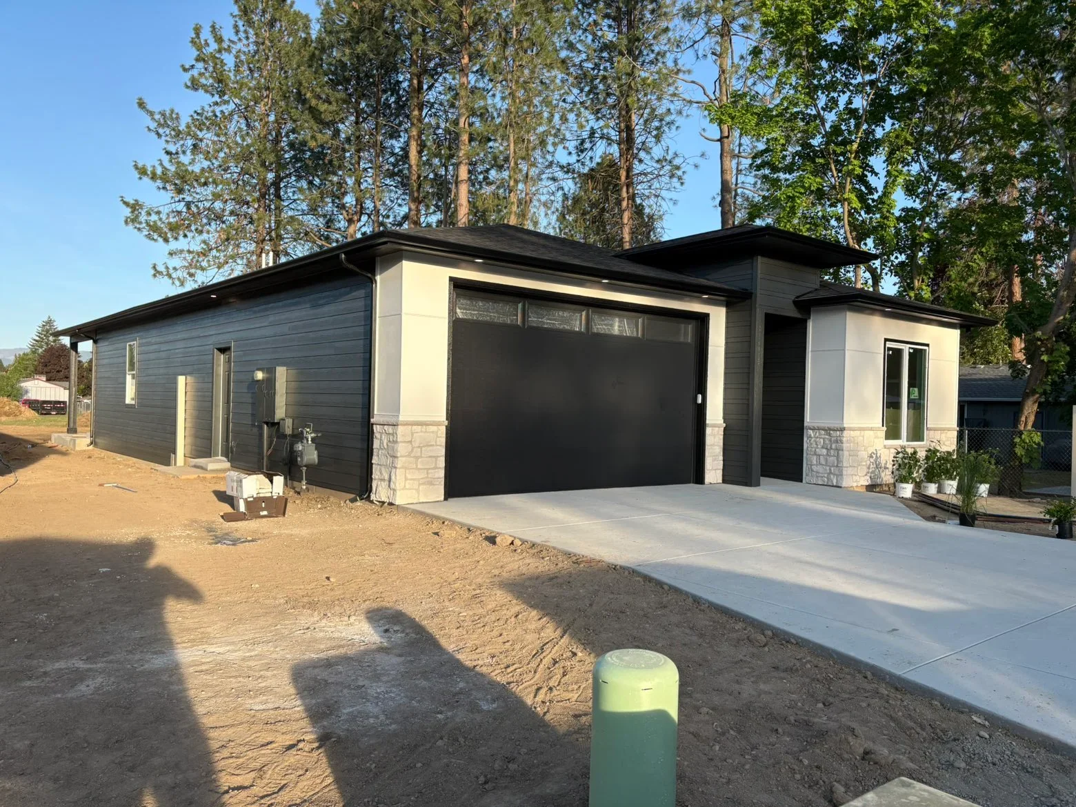 Black metal roof on modern garage with dark siding and stone veneer trim