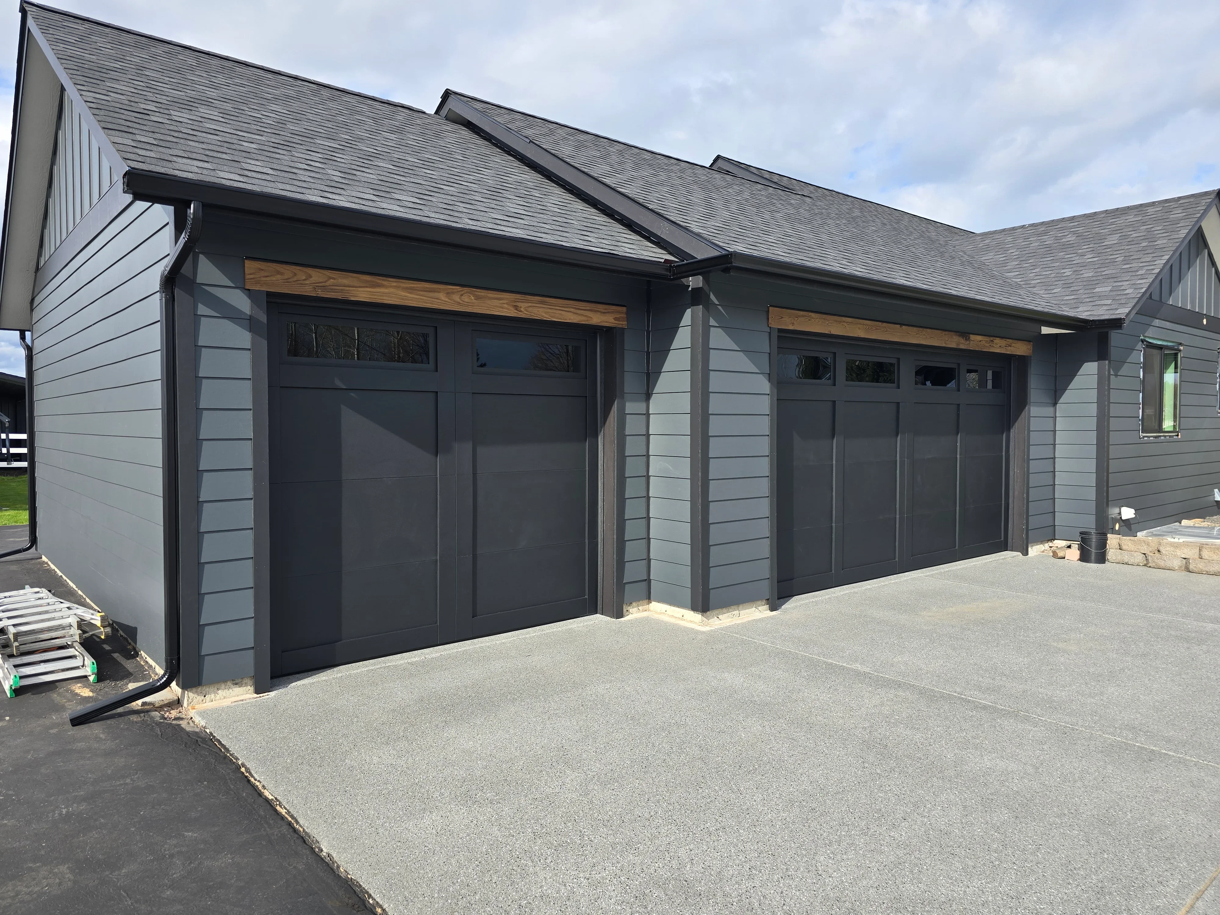 Gray architectural shingle roof on modern garage with black trim and wood accents
