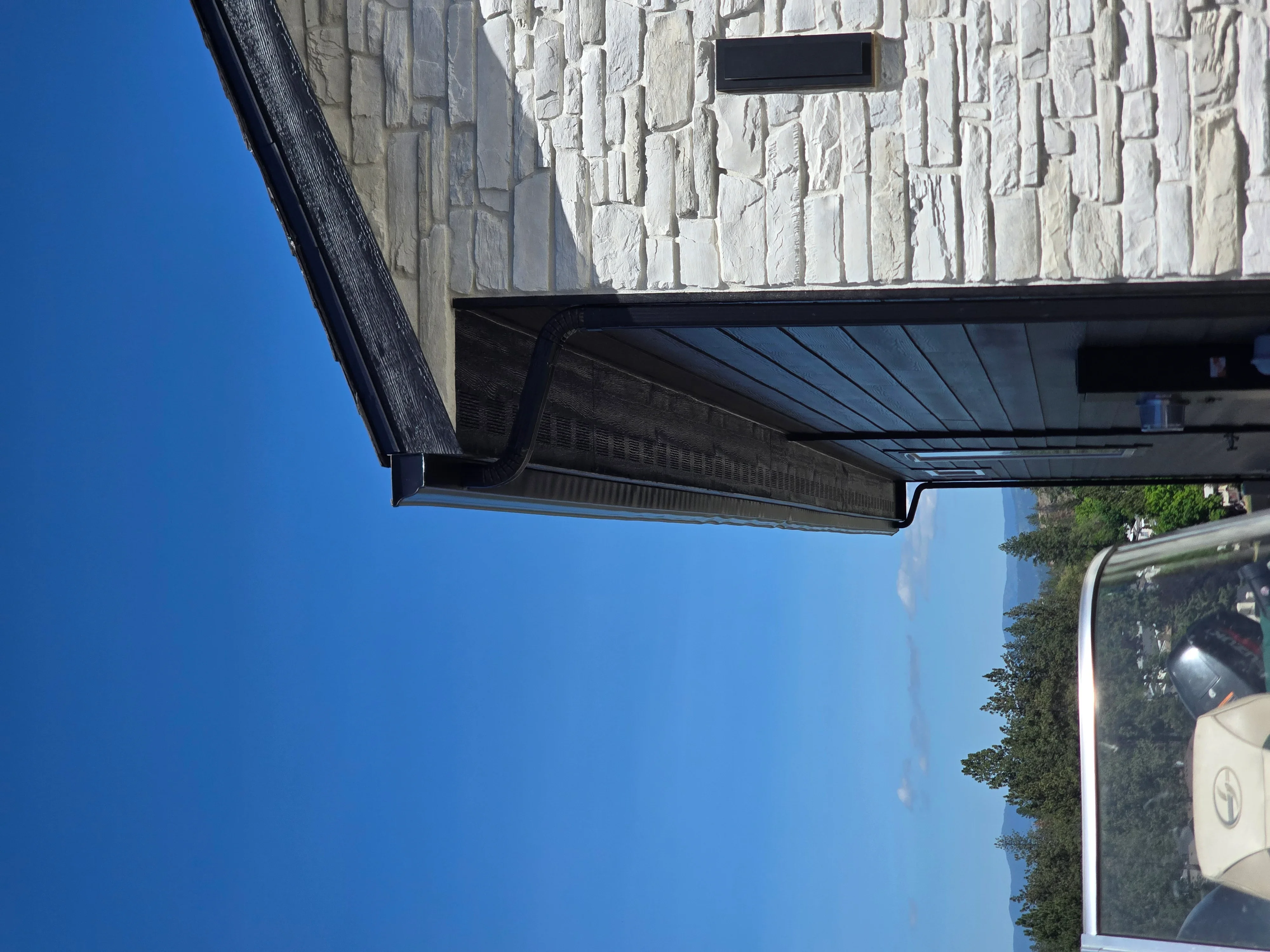 White stone veneer facade with black aluminum soffit and fascia trim