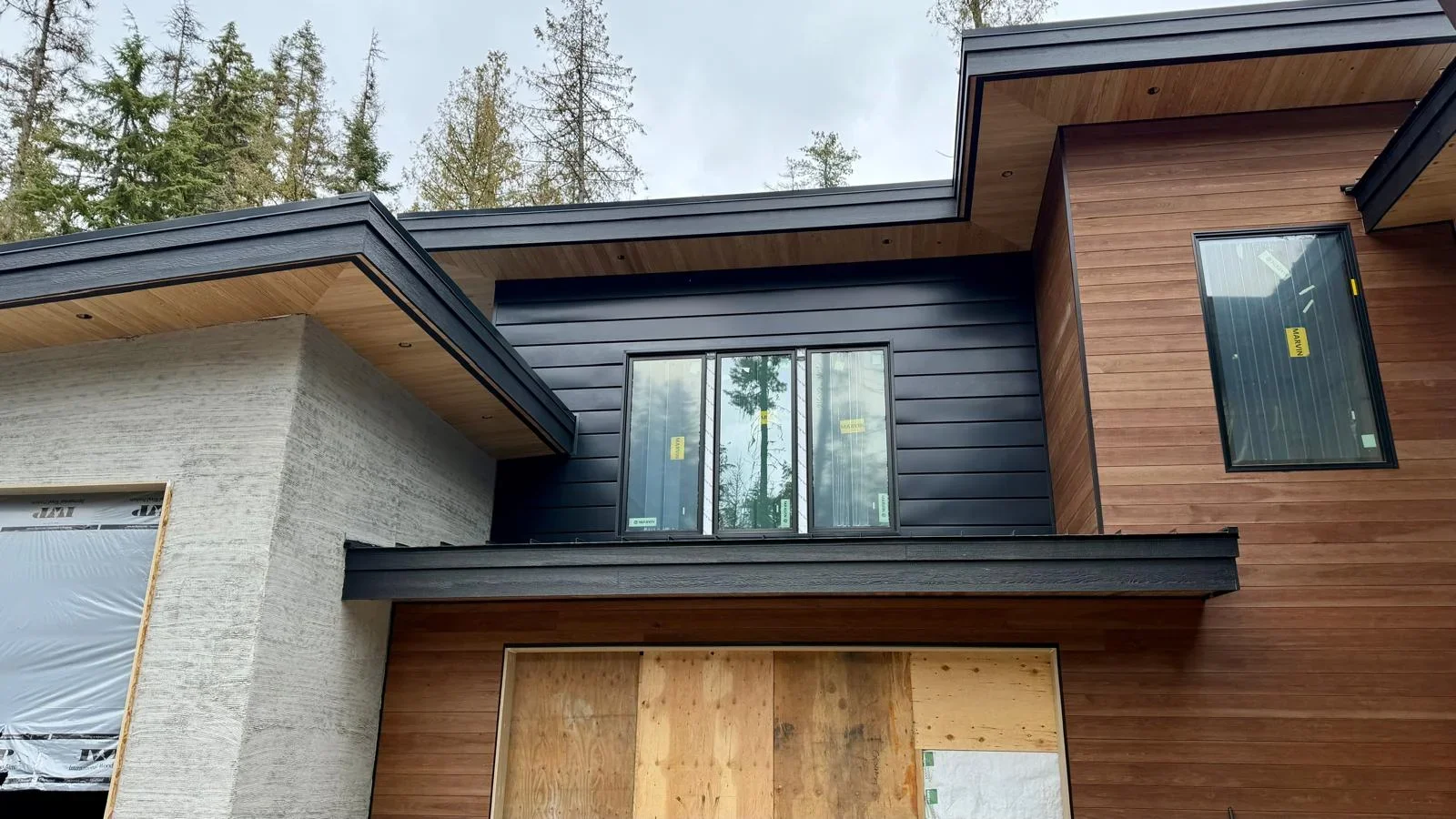 Black standing seam metal roof on modern home with wood soffit and mixed exterior materials