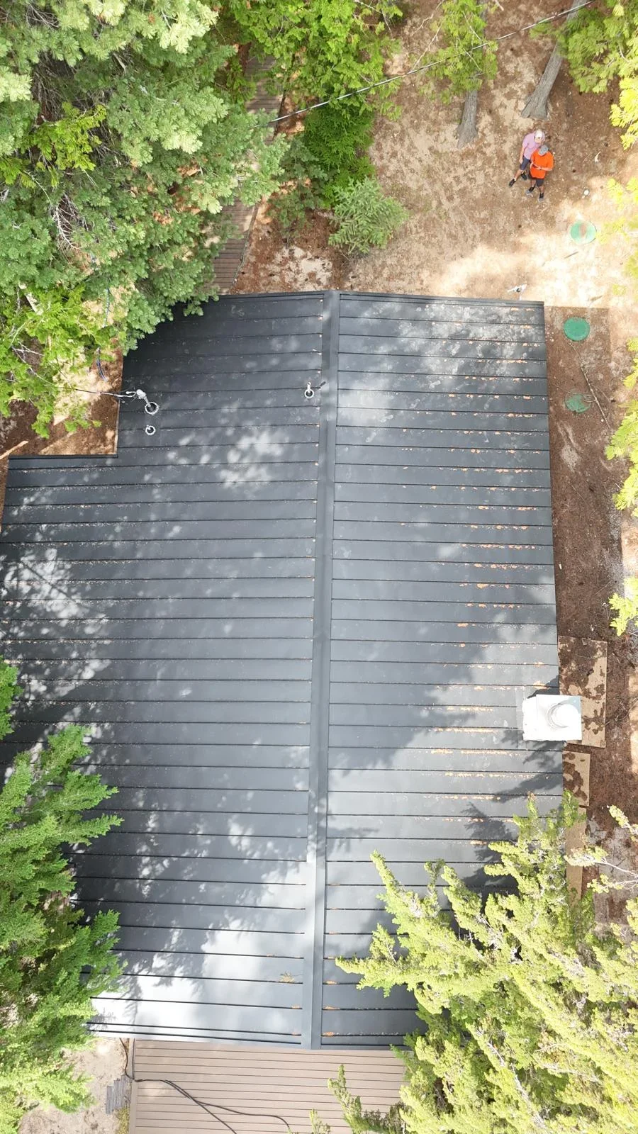 Black composite deck with horizontal boards and drainage system installed in wooded setting