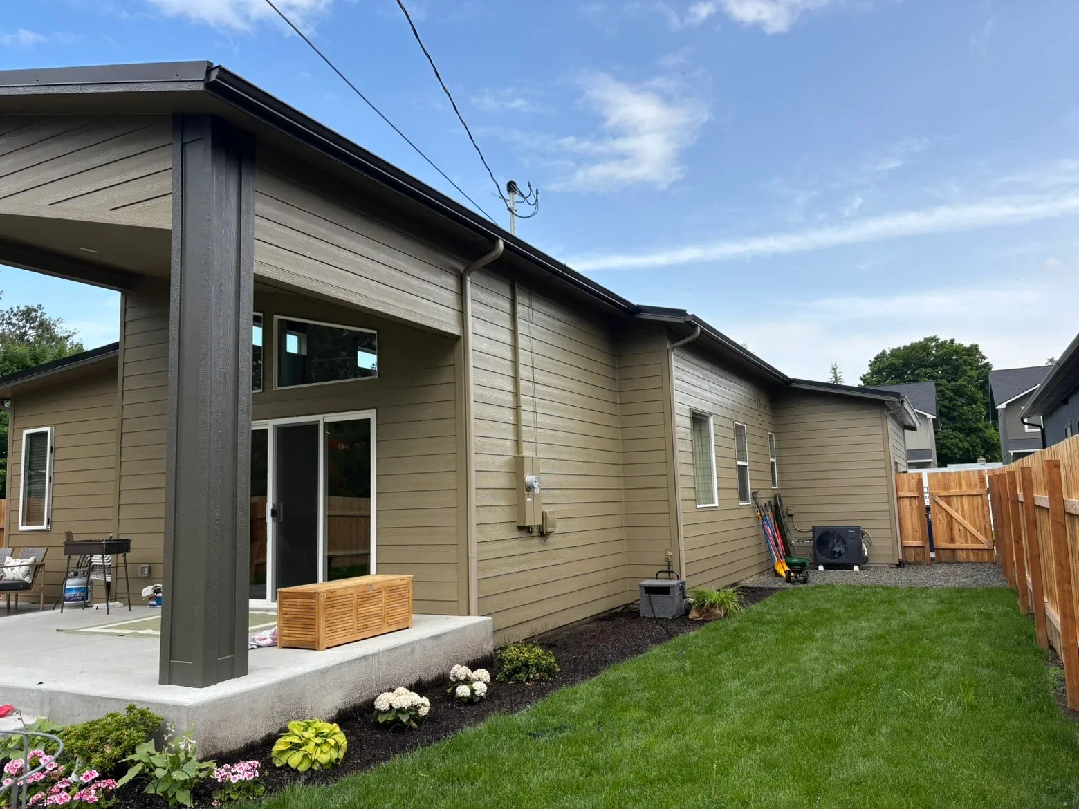 Black gutters and fascia on tan fiber cement siding with downspout installation