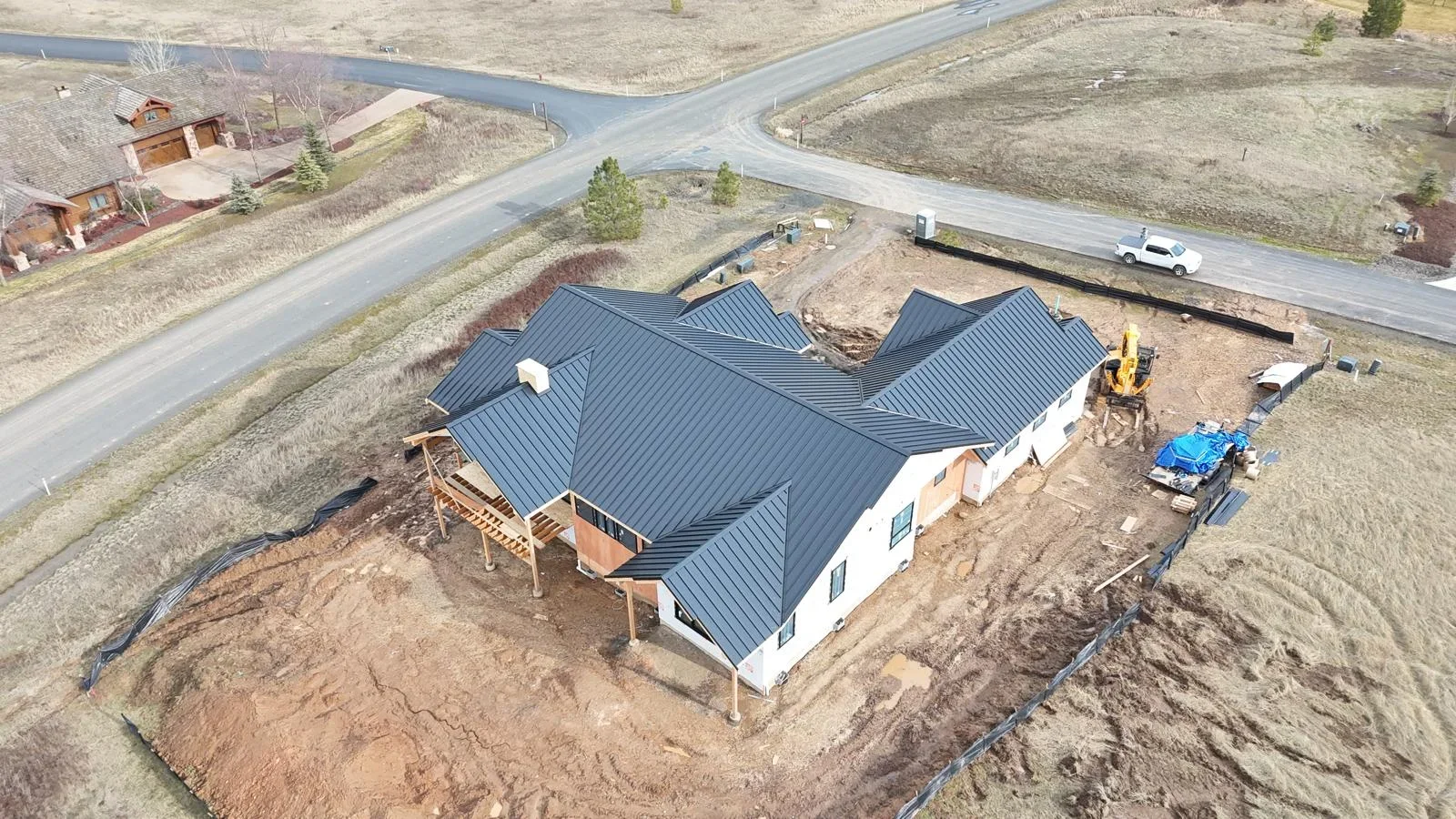 Standing seam metal roof installation on new residential home construction with white walls