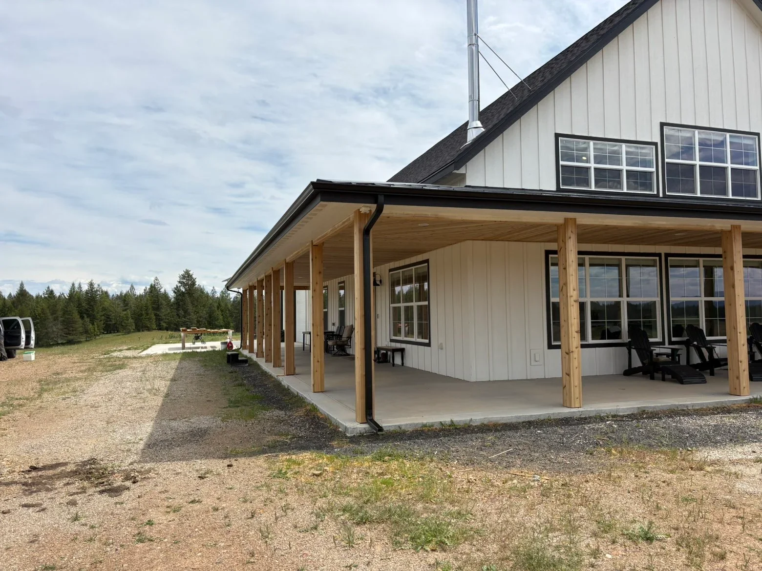 Dark asphalt shingle roof with metal gutters on modern farmhouse with metal siding and timber porch posts