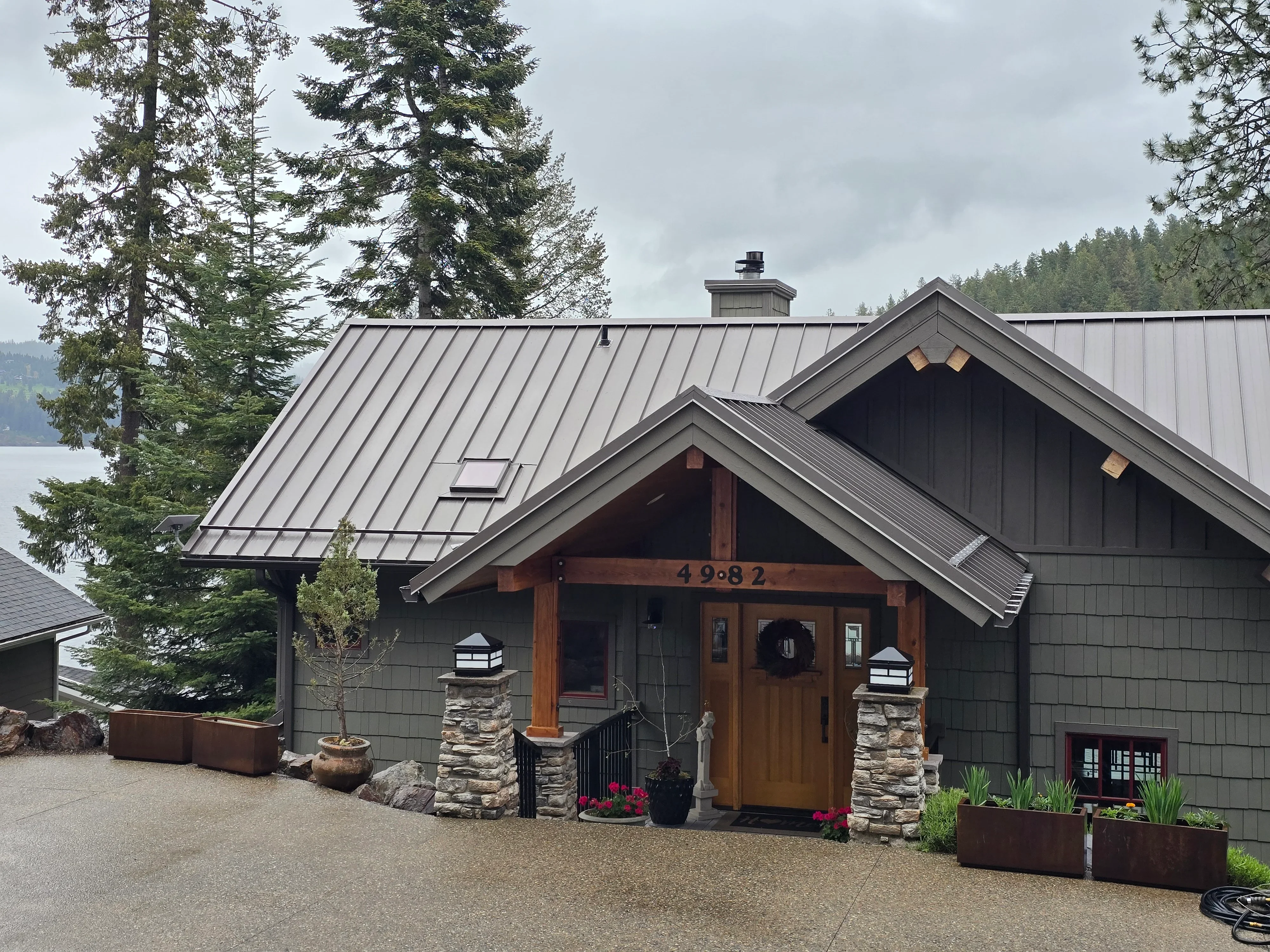 Standing seam metal roof with charcoal gray finish, multiple roof planes, and chimney flashing