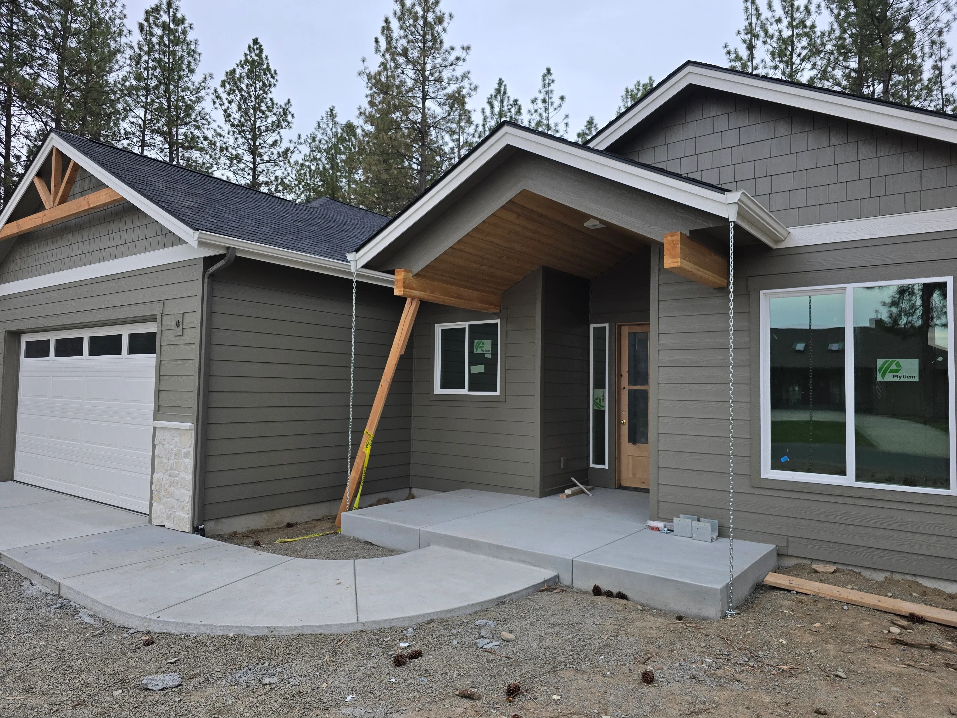 Black asphalt shingle roof with timber gable accents on gray siding home