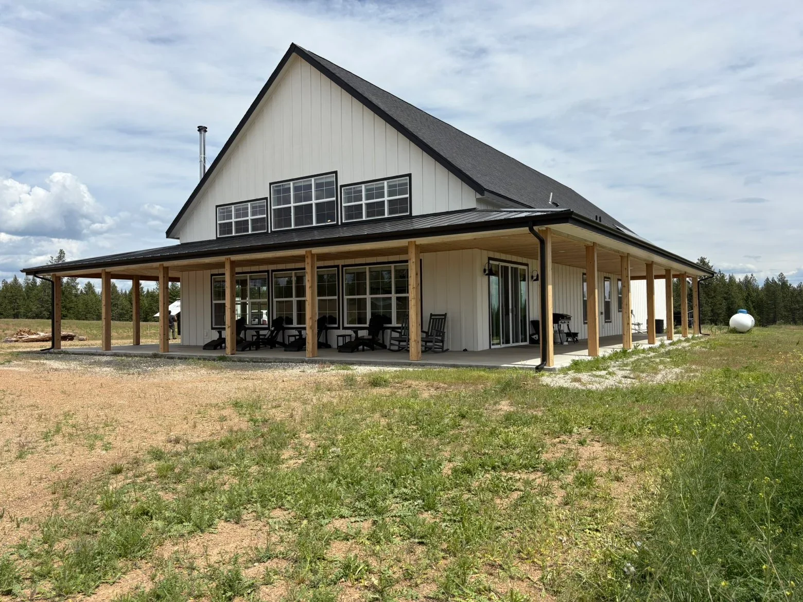 Standing seam metal roof on farmhouse with gable design and wooden porch columns