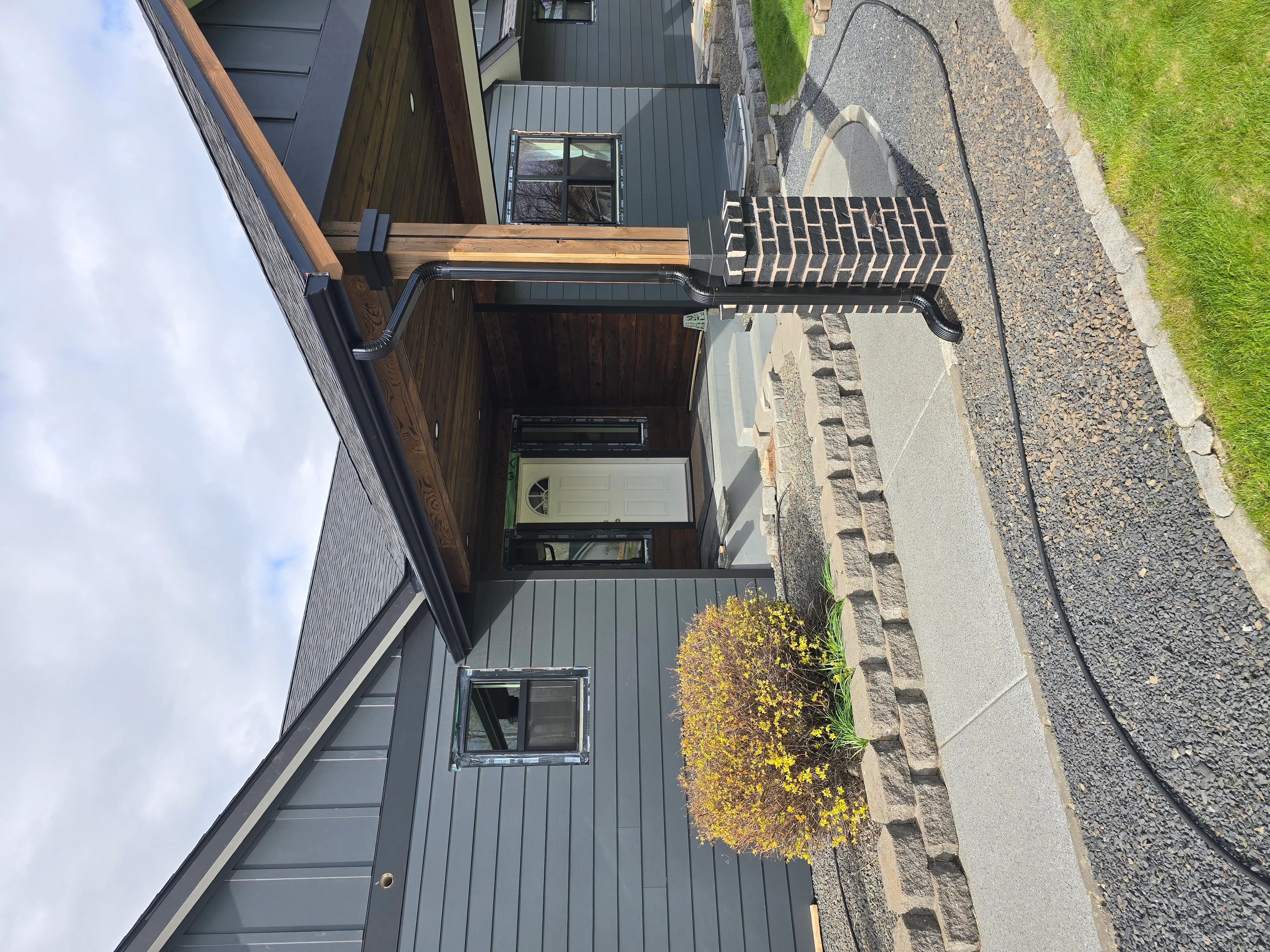Standing seam metal roof with charcoal gray panels and integrated gutter system