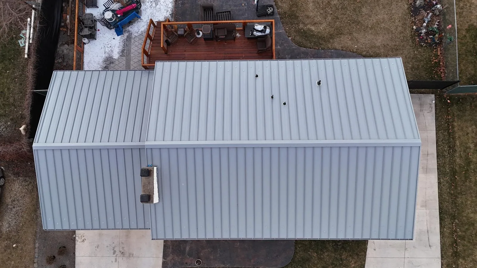 Aerial view of standing seam metal roof with vertical ribbed panels and roof penetrations