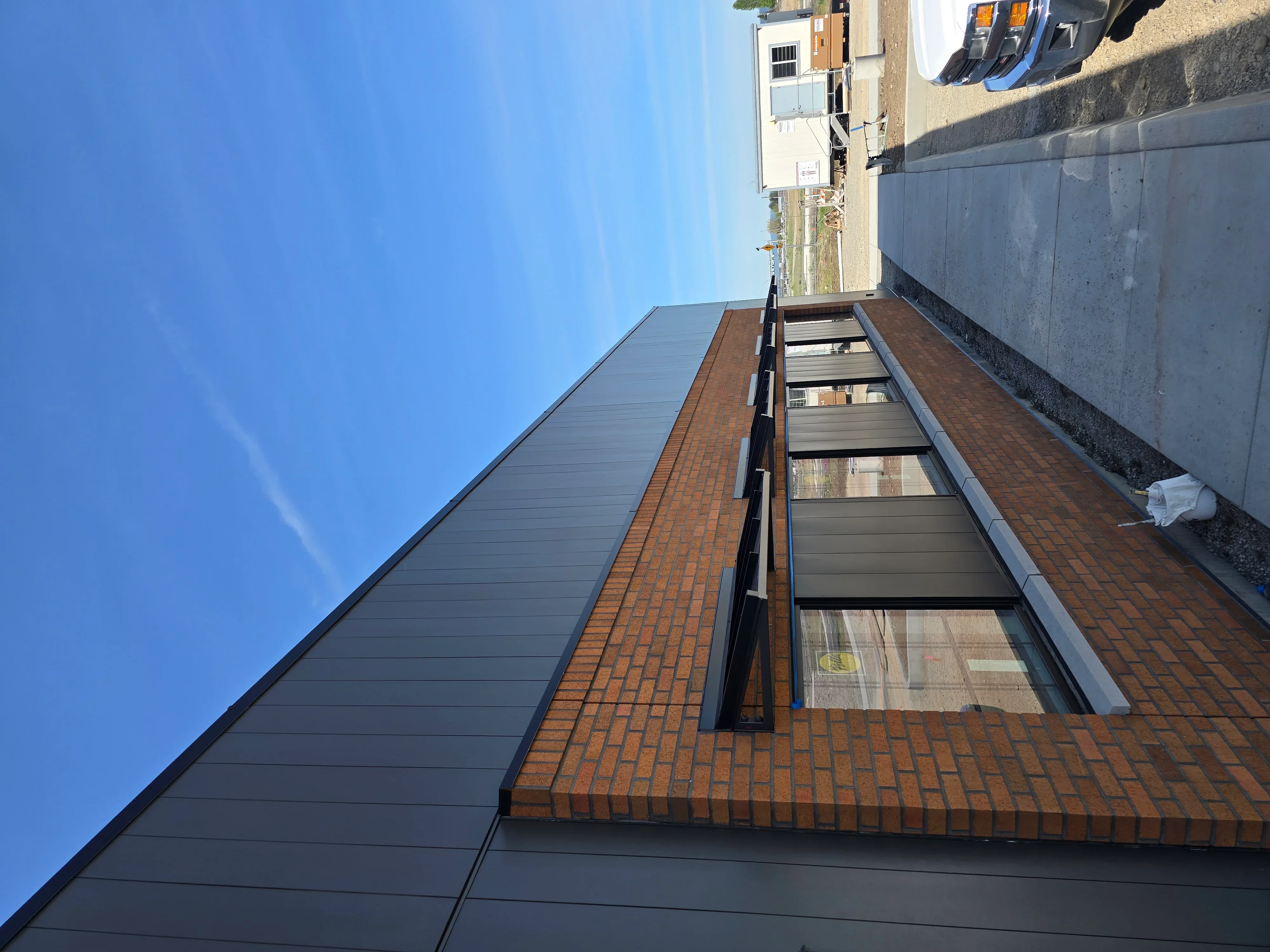 Dark slate roof installation with brick chimney, professional flashing and clean shingle lines