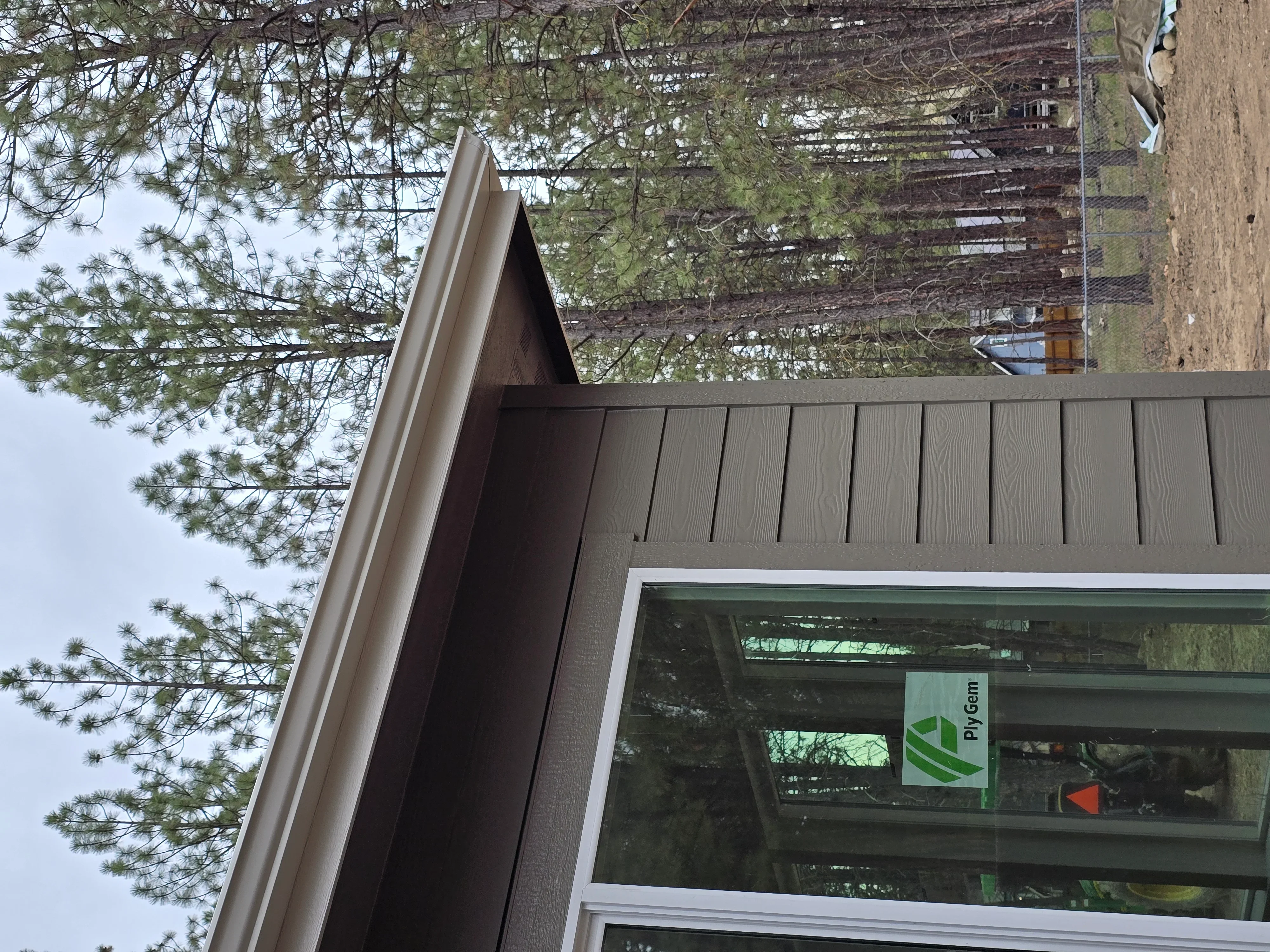 Dark composite vertical siding with white trim, soffit, and fascia on residential exterior