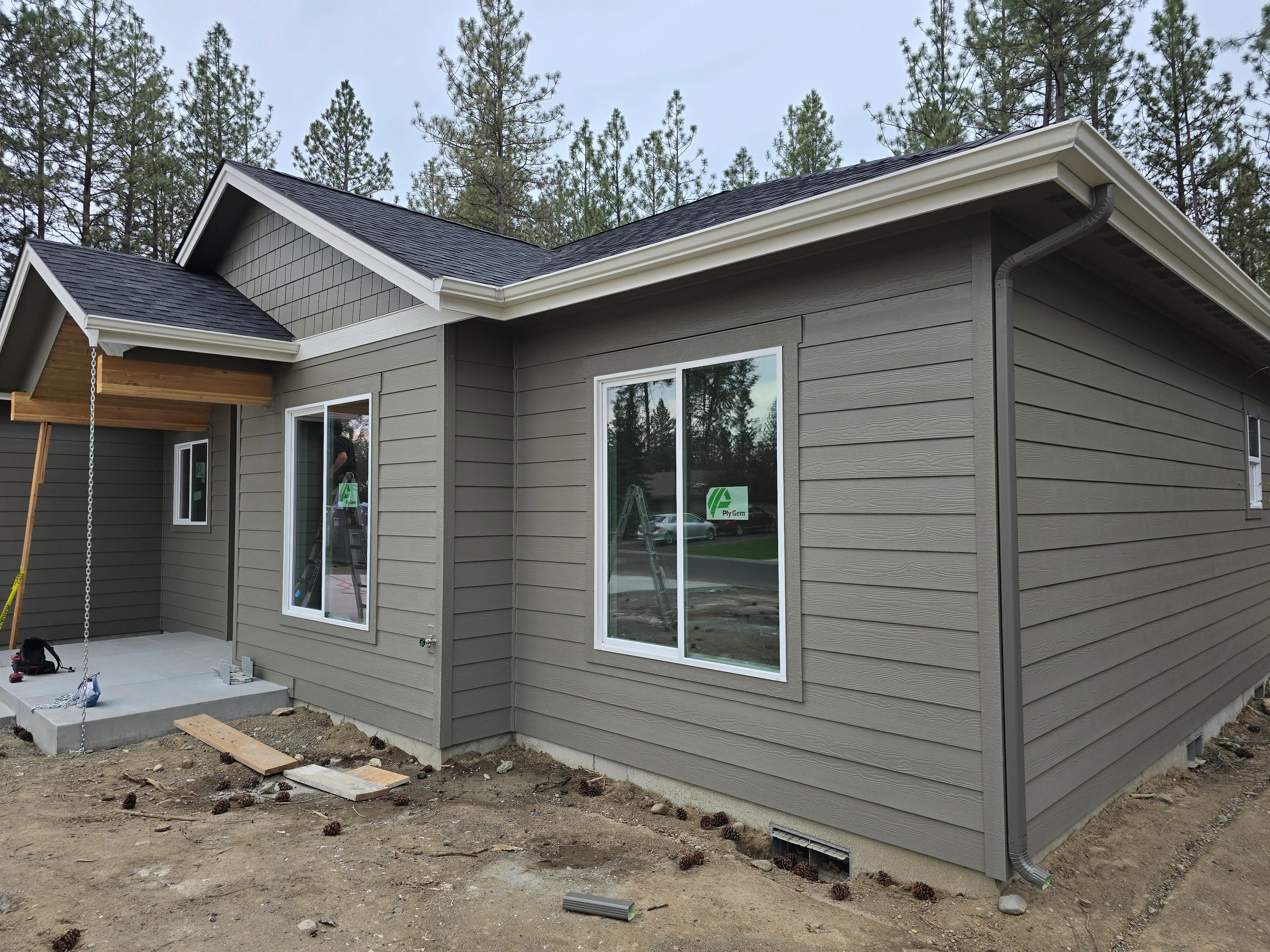 Dark asphalt shingle roof with white trim on new construction home with gray siding