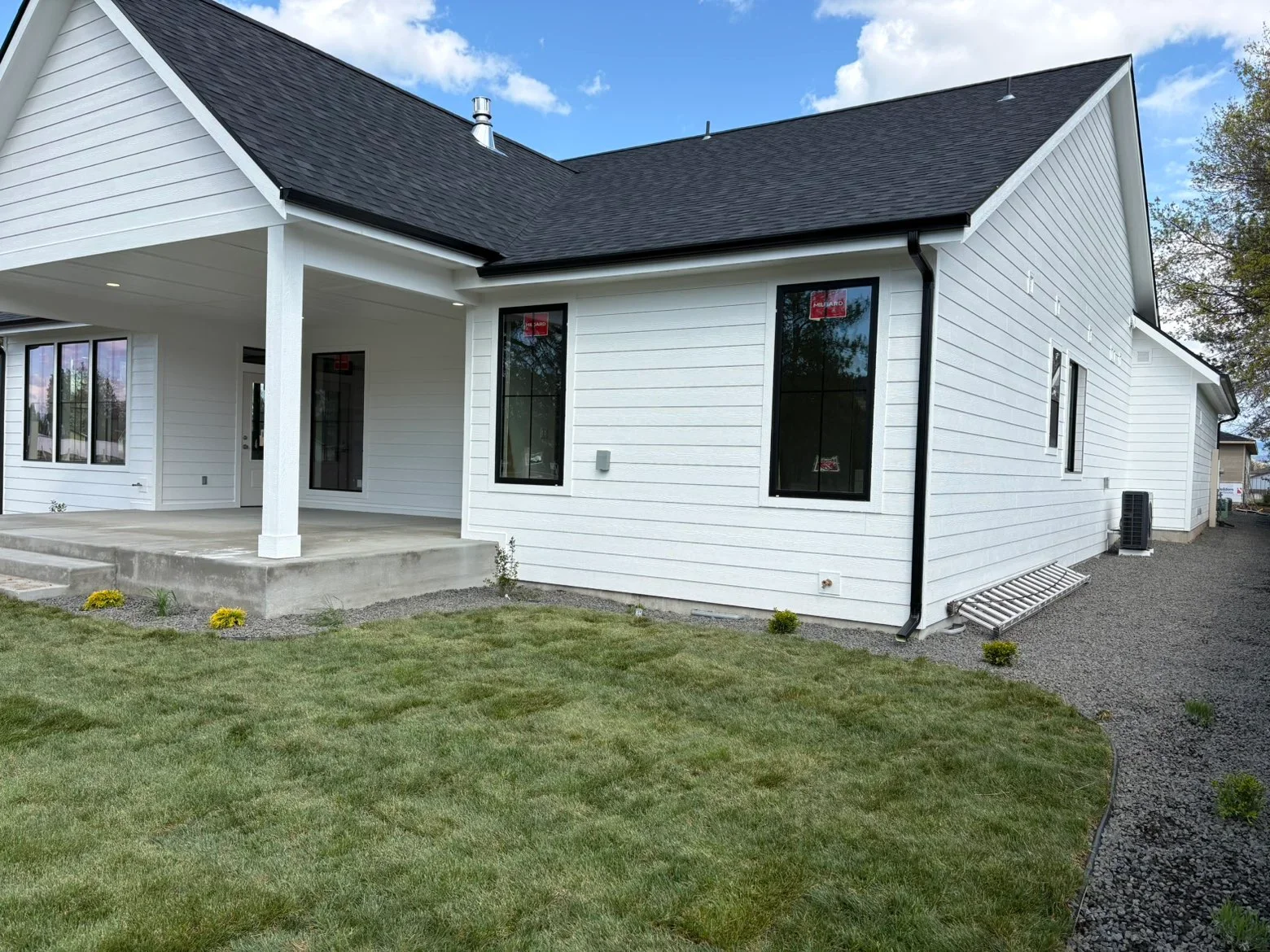 White farmhouse with charcoal gray asphalt shingle roof, covered porch, and black-trimmed windows