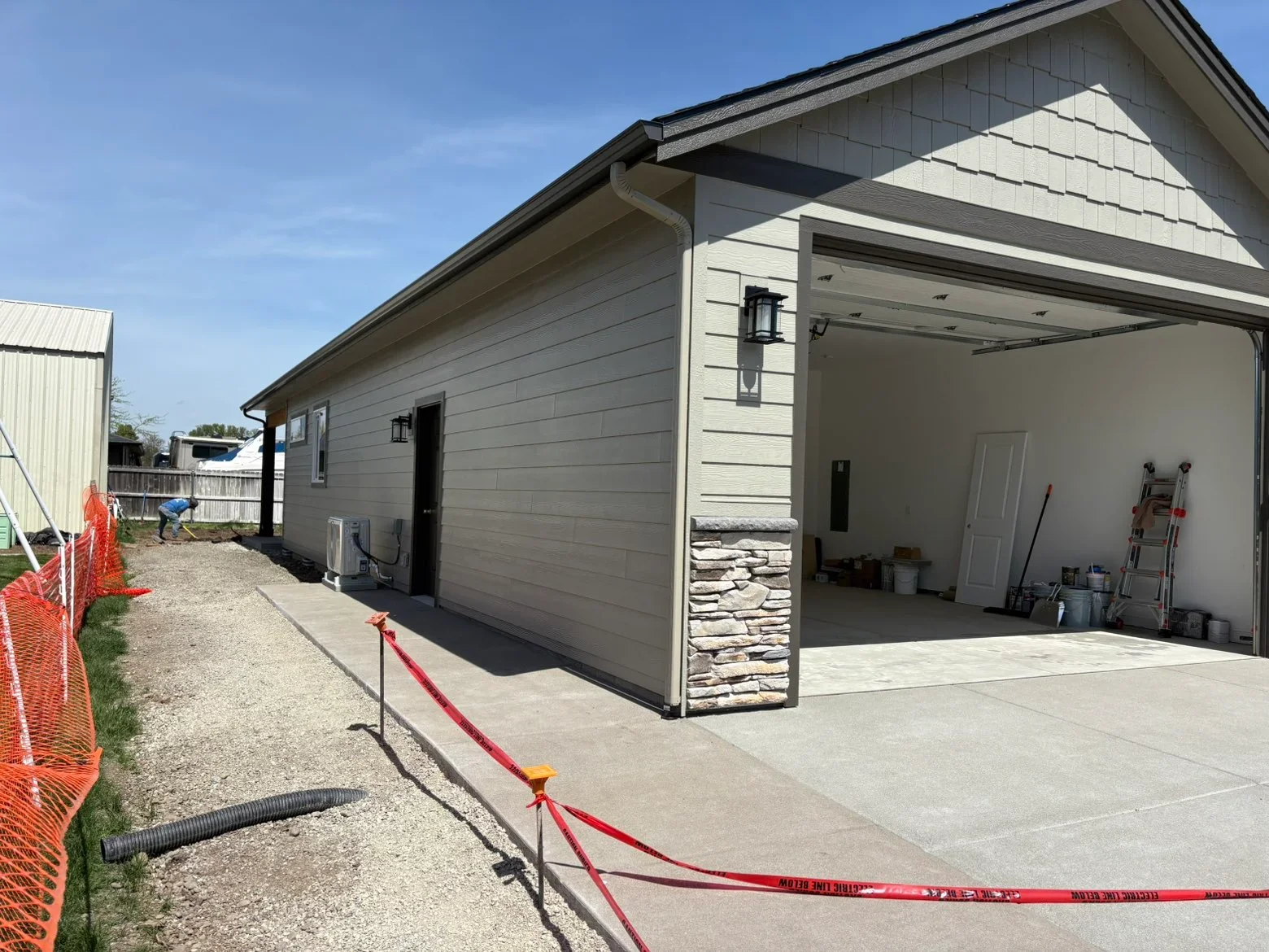 New garage addition with gray siding, stone veneer, concrete driveway, and pitched roof