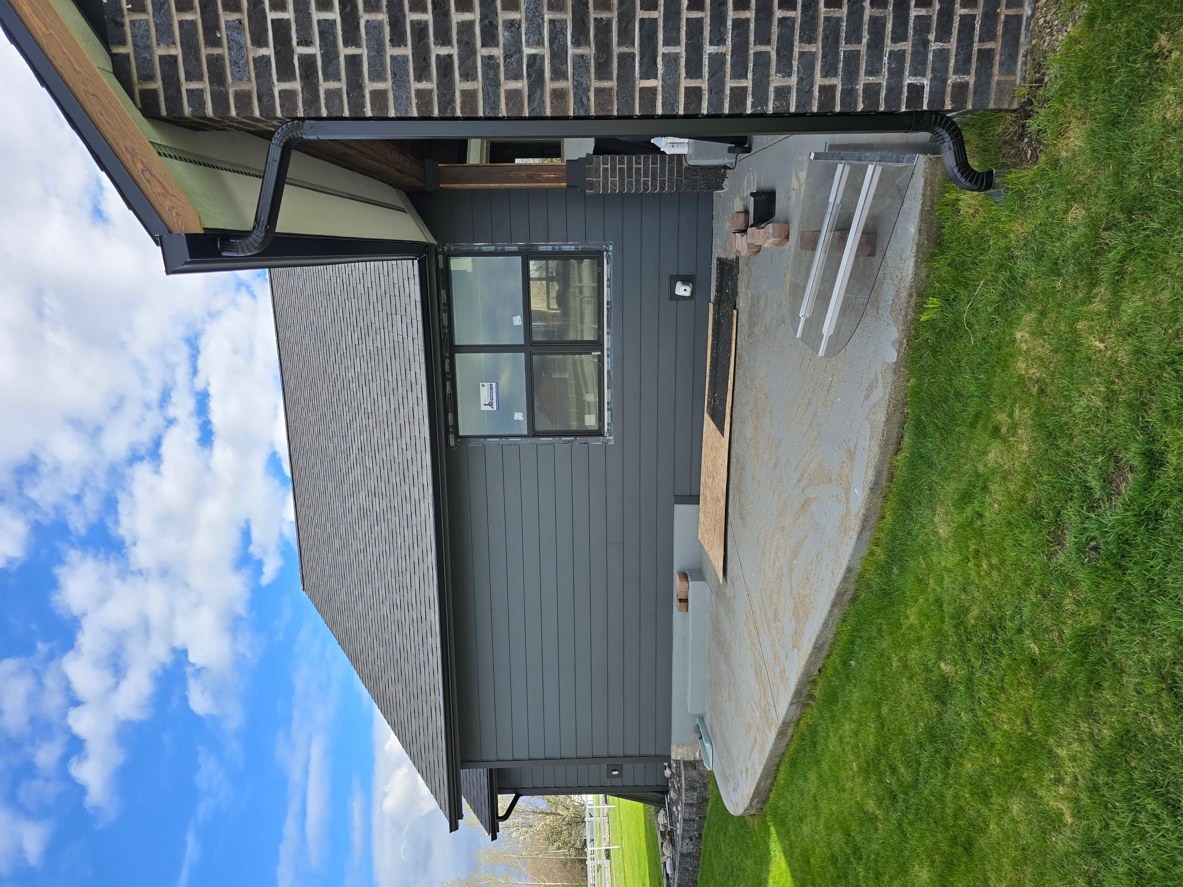 Standing seam metal roof and vertical siding on residential structure with integrated gutters