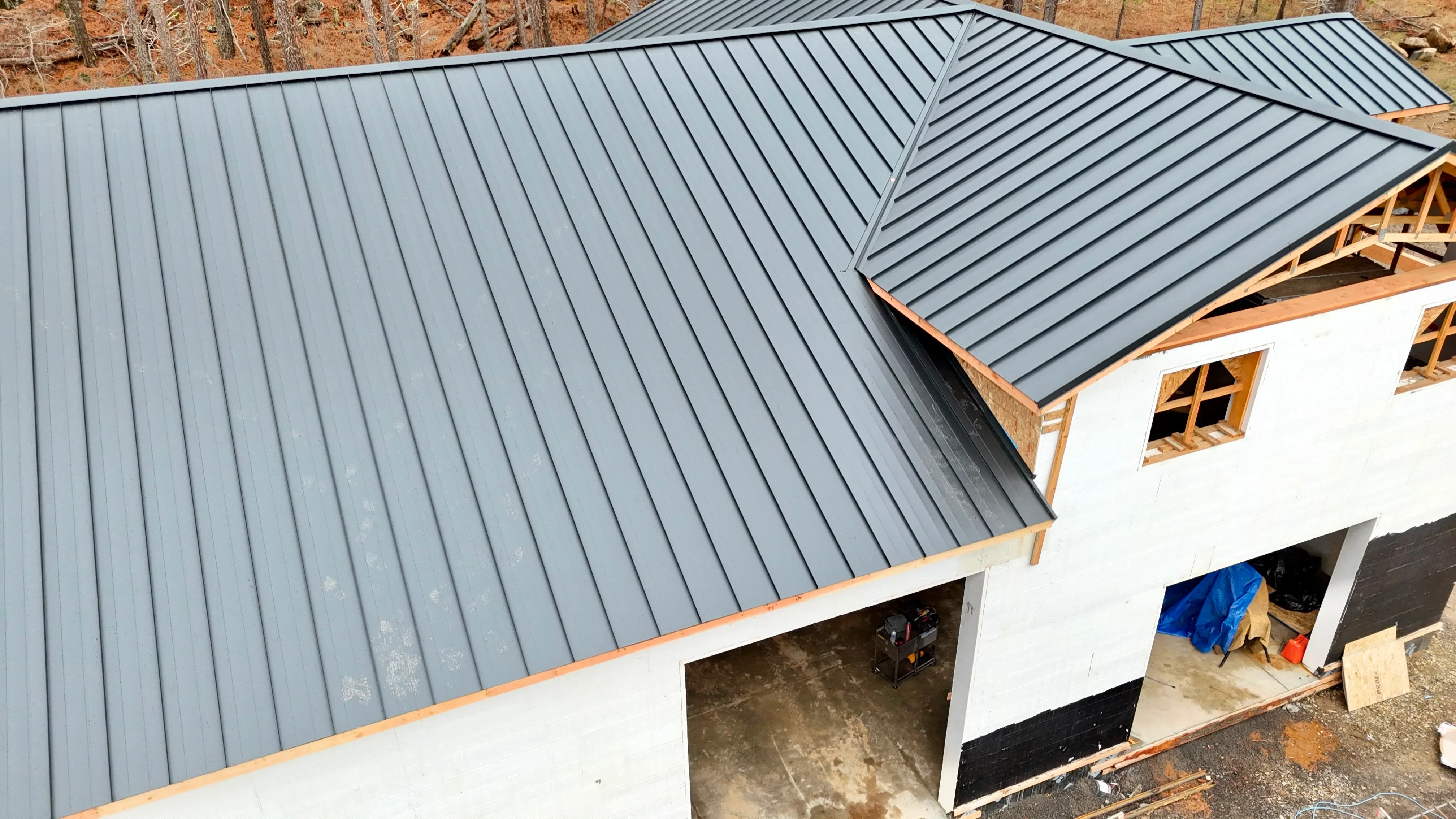 Gray standing seam metal roof with multiple planes and valleys on residential structure