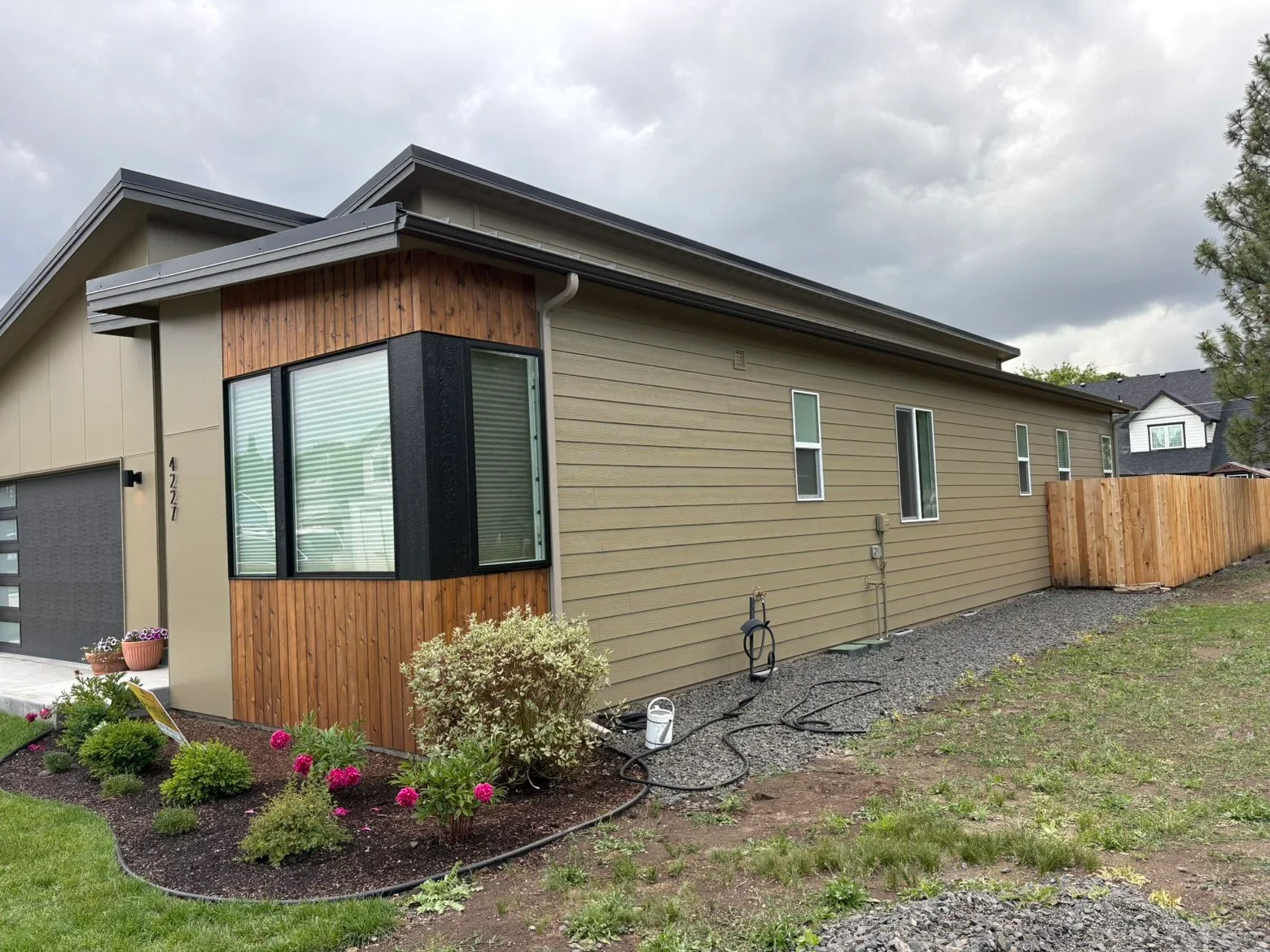 Modern home with tan fiber cement siding, wood accent bay window, metal roof, and updated windows